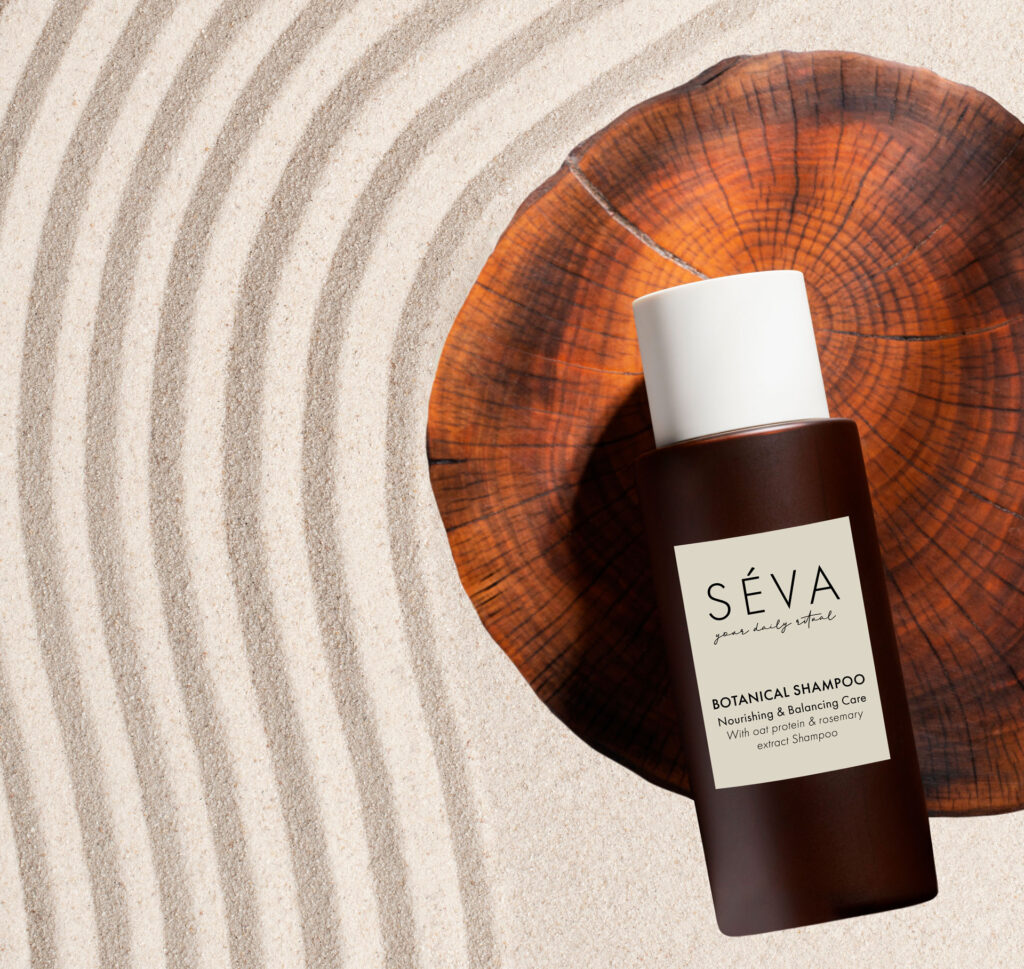 SÉVA hair care products displayed on sand texture background – minimal, amber packaging design for shampoo, serum and hair mask